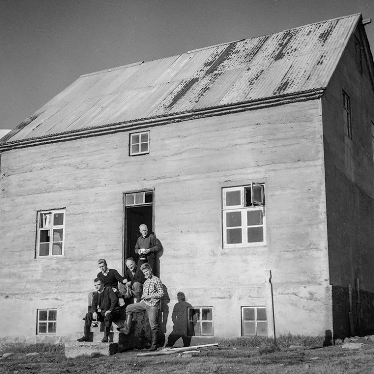 Þetta er Naustavík, eyðibýli í Náttfaravíkum, vestan Skjálfanda, nokkurn veginn gegnt Húsavík. Borin hafa verið kennsl á tvo mannanna: Í dyrunum stendur Árni Jóhannesson mjólkurfræðingur og fyrir framan hann er Jón Sigurgeirsson frá Helluvaði. Ólafur Jónsson, ráðunautur og rithöfundur,  tók þessa mynd.