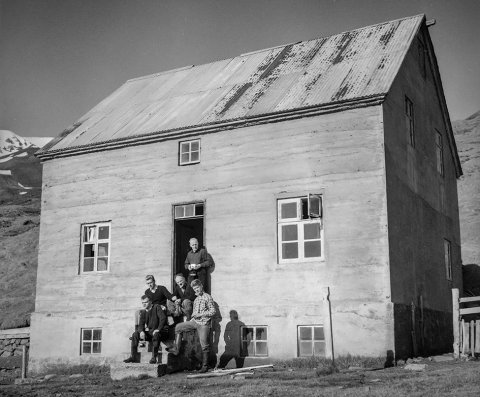 Þetta er Naustavík, eyðibýli í Náttfaravíkum, vestan Skjálfanda, nokkurn veginn gegnt Húsavík. Borin hafa verið kennsl á tvo mannanna: Í dyrunum stendur Árni Jóhannesson mjólkurfræðingur og fyrir framan hann er Jón Sigurgeirsson frá Helluvaði. Ólafur Jónsson, ráðunautur og rithöfundur,  tók þessa mynd.