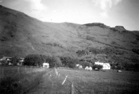 Múlakot í Fljótshlíð; báðir Múlakotsbæirnir. Til hægri er austurbærinn og húsið vinstra megin er vesturbærinn. Litla hvíta húsið á milli bæjanna er hús listmálaranna, eins og það mun hafa verið kallað. Á fyrri hluta tuttugustu aldar var Múlakot einkum þekkt fyrir þrennt, garðinn í Múlakoti, hótelið og listmálarana. Ásgrímur Jónsson málaði þar til dæmis oft. Nánar hér um Múlakot: https://mulakot.is/ - / m-stae1-6601 frá Minjasafninu á Akureyri