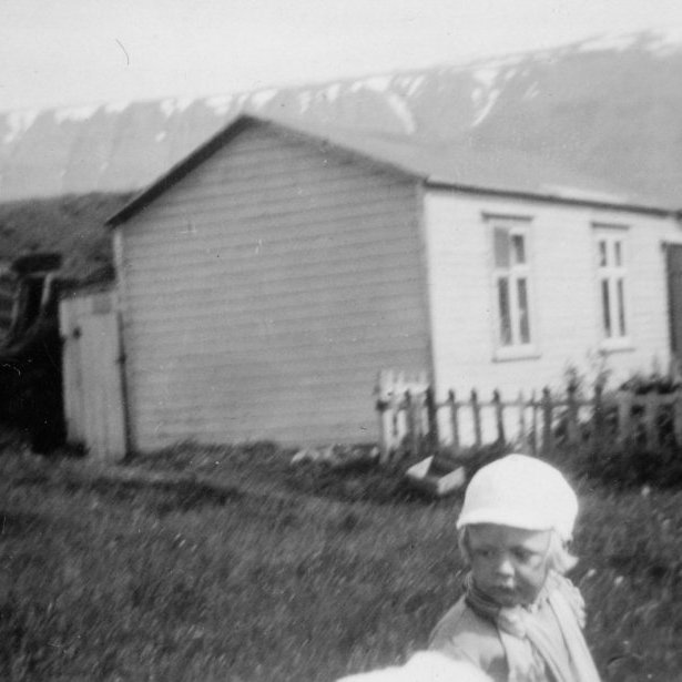 15 - 19.2.2021 - Þessi mynd er tekin aftan við núverandi bæjarhús á Saurbæ í Eyjafirði. Hvíta timburhúsið var byggt sunnan við torfbæinn haustið 1920 fyrir séra Gunnar Benediktsson. Lengst til hægri sér í steyptan kjallara íbúðarhússins sem byggt var fyrir séra Gunnar. Drengurinn á myndinni er Benedikt Gunnarsson, sonur Gunnars og fyrri eiginkonu hans, Sigríðar Gróu Þorsteinsdóttur. - Minjasafnið á Akureyri / Mynd 247-013