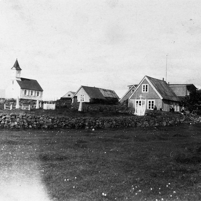 Þarna er Þingvallakirkja og Þingvallabærinn gamli. Kirkjan sjálf er reist 1859 en turninum er bætt við 1907 svo myndin er tekin eftir það en áður en gamli Þingvallbærinn var rifinn 1928 og húsin sem við þekkjum svo vel í dag voru reist 1930. Kirkjugarðshliðið hefur verið fært og er ögn lengra til norðurs í dag. Það sést móta fyrir Ármannsfelli til norðurs lengst til vinstri á myndinni. - m-stae1-15387 frá Minjasafninu á Akureyri