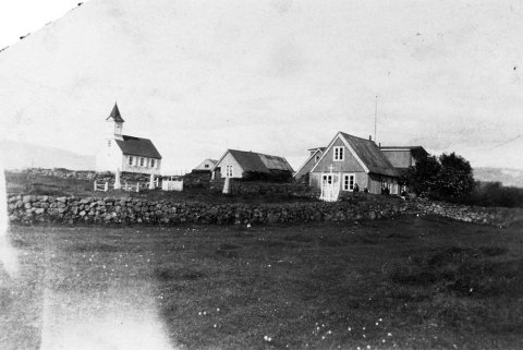 Þarna er Þingvallakirkja og Þingvallabærinn gamli. Kirkjan sjálf er reist 1859 en turninum er bætt við 1907 svo myndin er tekin eftir það en áður en gamli Þingvallbærinn var rifinn 1928 og húsin sem við þekkjum svo vel í dag voru reist 1930. Kirkjugarðshliðið hefur verið fært og er ögn lengra til norðurs í dag. Það sést móta fyrir Ármannsfelli til norðurs lengst til vinstri á myndinni. - m-stae1-15387 frá Minjasafninu á Akureyri