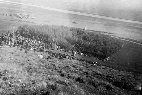 Þetta mun vera Aldísarlundur á Hrafnagili. Syðra-Laugaland handan árinnar. Lundurinn er kenndur við Aldísi Einarsdóttur á Stokkahlöðum sem var mikil ræktunarkona og hafði forgöngu um plöntun í lundinum. Í dag er þessi skógur gróinn saman við seinni tíma trjárækt í brekkunum ofan við Hrafnagil, skv. upplýsingum frá lesanda. Ábending barst um að sennilega sé myndin tekin á 50 ára afmæli KEA árið 1936. - m-stae1-15379 frá Minjasafninu á Akureyri