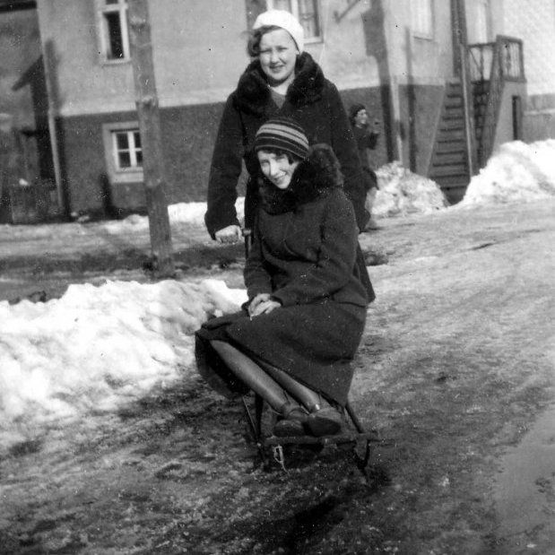 17 – Lesandi sendi eftirfarandi: Myndin er tekin á horni Glerárgötu og Gránufélagsgötu á Akureyri, horft er austur Gránufélagsgötu yfir Glerárgötu. Stúlkan sem situr sparksleðann er Anna Sigríður Eggertsdóttir Guðmundar byggingameistara frá Siglunesi sem byggði Gránufélagsgötu 11 og bjó þar ásamt Stefaníu Sigurðardóttur frá Kambhóli og 9 börnum. Stúlkan sem stendur er Hlín Jónsdóttir  Jónatanssonar járnsmiðs sem bjó í Glerárgötu 3 ásamt konu sinni Þórunni Friðjónssyni frá Sandi. Anna var fædd 1910 og Hlín 1911 og voru þær vinkonur og nábúar. Tvö húsin sem er nær eru farin í dag og húsið sem er næst var kallað Guðmundarhús en þar átti heima Guðmundur og fjölskylda, einn sonur þeirra er Jón Oddgeir Guðmundsson sem í dag býr í og á Glerárgötu 1. Hann á líka „Litlu búðina“ sem er þar í bakhúsi og selur hann þar t.d. bílabænina. Næsta hús þarna var kallað Strýta og Ferðafélagið fékk það hús og flutti að ég held inn í Herðubreiðalindir og er þetta hús skáli þar í dag. Húsið sem sér aðeins í gaflinn á er Gránufélagsgata 19. -  Minjasafnið á Akureyri / Mynd 080-030