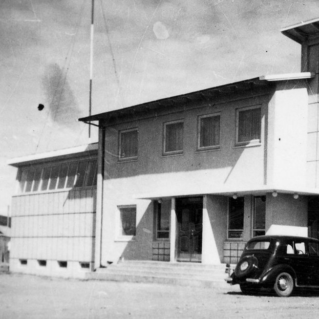 Þetta er Garðarsbraut 21 á Húsavík. Elín Björg Ragnarsdóttir skrifaði eftir að myndinni var deilt á Facebook síðunni Gamlar ljósmyndir: „Þetta er gamla heimilið mitt Póstur og sími Húsavík. Pabbi var stöðvarstjóri þarna frá 1962-1987 og var íbúð á efri hæðinni fyrir fjölskyldu stöðvarstjóra líkt og var víða um land á þessum árum. Koparþak var sett á lægri bygginguna vegna leka fljótlega eftir að pabbi kom norður þannig að gluggaröndin efst er ekki lengur til staðar heldur koparfrontur. Upp úr 1980 var byggt við húsið og hýsir sá hluti nú Vínbúðina en gistiheimili er í þeim hluta sem er á tveimur hæðum. Síminn er svo með restina af húsinu í dag.“ / m-stae1-16119 frá Minjasafninu á Akureyri