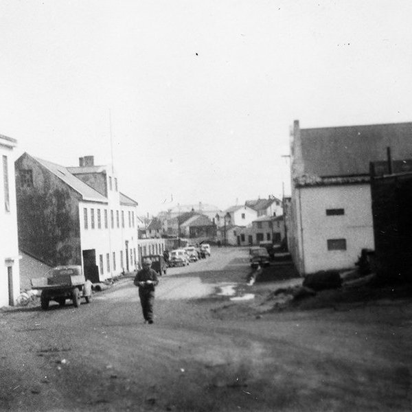 Þetta er í Vestmanneyjum. Myndin er tekin austur Strandveg, fremstu húsin bæði vinsta og hægra megin eru svokölluð Sælahús, skv. upplýsingum sem bárust. Annað húsið vinstra megin, það reisulega með kvistinum, er Magnahúsið sem svo er kallað – þar var Vélsmiðjan Magni með starfsemi en í húsinu nú rekið veitingahúsið Slippurinn. - / m-stae1-16289 frá Minjasafninu á Akureyri