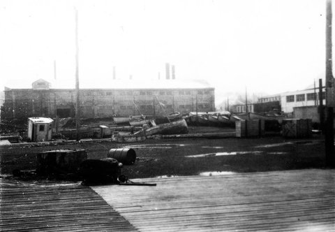 Myndin er frá Vestmannaeyjum. Lesandi sendi eftirfarandi: Þetta svæði var sunnan núverandi fiskimjölsverksmiðju Vinnslustöðvarinnar (VSV) (mjölhús á myndinni) og austan fiskvinnsluhúss Vinnslustöðvarinnar. Þarna standa núna fiskvinnsluhús Vinnslustöðvarinnar. - / m-stae1-16300 frá Minjasafninu á Akureyri