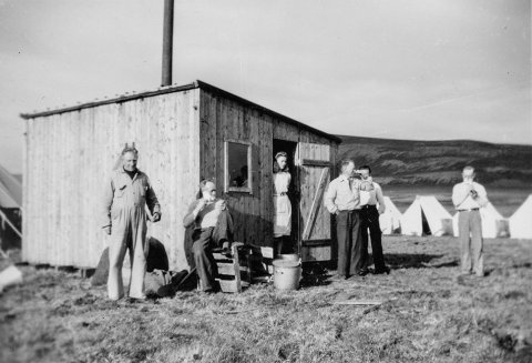 Talið er líklegt að á myndinni sé vegavinnuflokkur en hvorki hafa borist ágiskanir um hvaða fólk er á myndinni eða hvar hún er tekin. Lesandi sendi þó þessa bráðskemmtilegu lýsingu: „Þetta er augljóslega vegavinnuhópur og matarskúrinn í forgrunni en þar hafði ráðskonan lítið afþiljað herbergi. Tjöldin voru svo reist allt í kring og svona búðir voru á mörgum heiðarvegum um allt land. Greinilega helgarleyfi fram undan og karlarnir að raka sig og funsa sig fyrir heimferð yfir bláhelgina.“ - Þeir sem kunna að búa yfir upplýsingum um myndina eru hvattir til að senda þær á netföngin hg@minjasafnid.is og skapti@akureyri.net - / m-stae1-16483 frá Minjasafninu á Akureyri