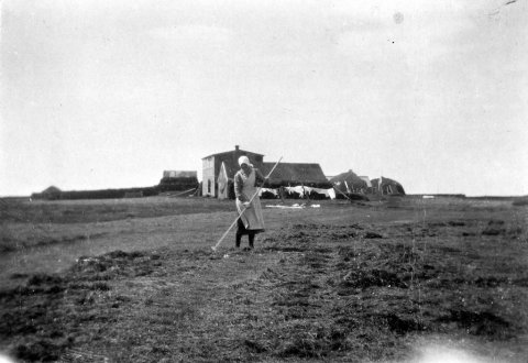 22 - 9.4.2021 - Myndin er af bænum Hvoli í Mýrdal, tekin af séra Sveinbirni Högnasyni sem ólst þar upp. Konan er Anna Eyjólfsdóttir, heimasæta á bænum. Þorsteinn Jónsson, afabarn sr. Sveinbjörns segir myndina að öllum líkinduma tekna árið 1923, hann eigi fleiri myndir í fjölskyldualbúmi sem líklega séu teknar sama dag.- Minjasafnið á Akureyri / Album 29-357