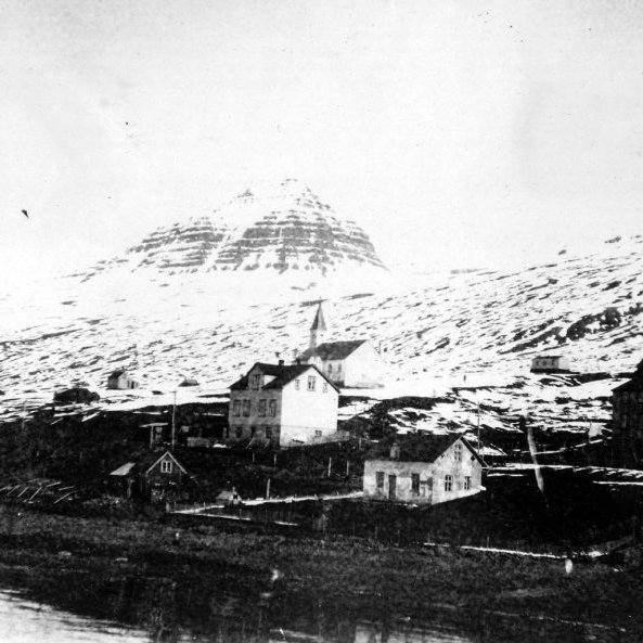 24 - Frá Búðum í Fáskrúðsfirði og Fáskrúðsfjarðarkirkja. Stóra húsið á miðri mynd heitir Ás en það brann einhvern tíma um 1970. Litla húsið (hvítt) sem lúrir þar skáhallt fyrir neðan heitir Dvergasteinn en það var rifið fyrir mörgum árum. Fjallið sem vakir yfir Fáskrúðsfirði heitir Hoffell. - Minjasafnið á Akureyri / Album 029-199