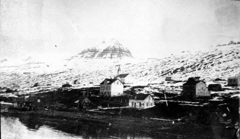 24 - Frá Búðum í Fáskrúðsfirði og Fáskrúðsfjarðarkirkja. Stóra húsið á miðri mynd heitir Ás en það brann einhvern tíma um 1970. Litla húsið (hvítt) sem lúrir þar skáhallt fyrir neðan heitir Dvergasteinn en það var rifið fyrir mörgum árum. Fjallið sem vakir yfir Fáskrúðsfirði heitir Hoffell. - Minjasafnið á Akureyri / Album 029-199