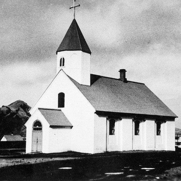 Þetta er Landakirkja í Vestmannaeyjum. Bygging kirkjunnar hófst árið 1774 og lauk 1778, og er hún þriðja elsta steinkirkja hér á landi, á eftir Viðeyjarkirkju og dómkirkjunni á Hólum. Lítil forkirkja (anddyri), sem sést á myndinni, var reist við vesturdyr kirkjunnar árið 1903 og á árunum 1955 til 1959 var byggð sú forkirkja og turn sem einkenna kirkjuna í dag. Myndin er því tekin einhvern tíma fyrir 1955. - / m-stae1-17071 frá Minjasafninu á Akureyri