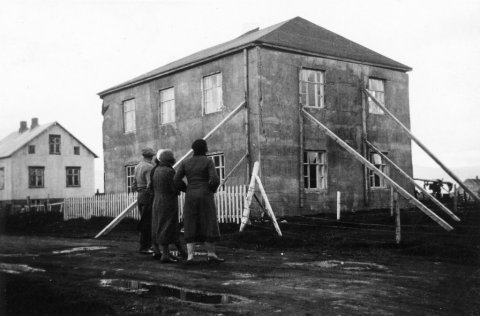 Þetta er húsið Lambhagi á Dalvík eftir stóra jarðskjálftann 2. júní 1934 sem talinn er hafa verið um 6,3 á Richter-kvarða og olli gríðarlegum skemmdum. Þarna sést suðurgaflinn og vesturhlið hússins. Norðurgaflinn hrundi út, en suðurgaflinn hékk uppi. Norðan við er Vallholt. Efri hæð Lambhaga skemmdist svo mikið í skjálftanum að hún var rifin en neðri hæðin stendur. Húsið er númer 7 við Skíðabraut. / m-stae1-17179 frá Minjasafninu á Akureyri