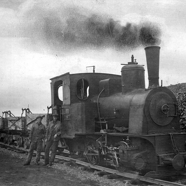 Myndin er tekin um 1925, í Reykjavíkurhöfn. Þetta er Eimreiðin Pionér í Austurhöfn, við hlið hennar standa eimreiðarstjórarnir Guðmundur Guðmundsson, til vinstri, og Páll Ásmundsson. Minør, systurlest Pionér, stendur á hafnarbakkanum við gömlu höfnina í Reykjavík á hverju sumri. Á vef Faxaflóahafna segir um þær: Eimreiðin Minør hefur ávallt verið í vörslu Faxaflóahafna yfir vetrartímann á meðan eimreiðin Pioner hefur verið varðveitt allt árið í kring á Árbæjarsafni. Eimreiðarnar voru keyptar hingað til lands vegna hafn­ar­gerðar.  Þar að auki var járn­braut lögð frá Öskju­hlíð,  Kringlumýri og Skóla­vörðuholt­inu./ m-stae-5-0417 frá Minjasafninu á Akureyri