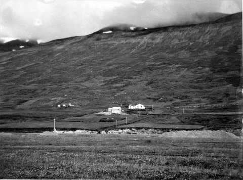 Þetta er bærinn Hlíð í Skíðadal. Vignir Sveinsson sendi eftirfarandi upplýsingar: „Þetta umhverfi þekki ég vel, enda fæddur og uppalinn á Þverá sem er beint á móti Hlíð. Myndin hefur verið tekin annað hvort 1957 eða 1958, líklega síðsumars 1957. Þarna er fjós í byggingu en aðeins búið að reisa hlöðuna sem er á bakvið fjósið. Byggingarár fjóssins er skráð 1958 í fasteignamati. Á myndinni sést einnig stór malarhaugur sem ýtt hefur verið upp úr eyrunum vestan ár, líklega vegna þessarar byggingar og/eða vegna íbúðarhúss sem byggt var á Þverá á sama tíma. Íbúðarhúsið þar var hlaðið úr r-steinum sem voru steyptir um haustið 1957 en húsið ekki reist fyrr en 1958 og þá jafnframt steyptar plötur. Mögulega gæti þessi malarbingur einnig hafa verið til ofaníburðar í þjóðveginn í dalnum.“  / m-stae5-1590 frá Minjasafninu á Akureyri