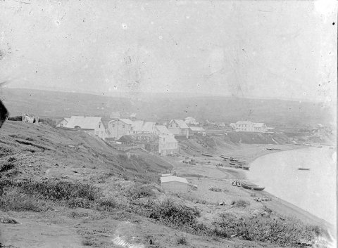 Þessi mynd er frá Húsavík. Margir lesendur voru sammála um það og bent var á að myndin væri tekin fyrir 1907 því ekki sé búið að byggja kirkjuna. Í pósti frá einum segir: Húsaþyrpingin í forgrunni eru KÞ húsin og stóru húsin hægra megin eru sennilega Guðjonhsen húsin, verslun-vöruhús-heimili.
Gilið rétt sunnan við þau hús er Búðarárgilið, þar sem Búðaráin rennur til sjávar, en hún á upptök í Botnsvatni sem er skammt fyrir ofan Húsavík, uppundir Reykjaheiði. / m-stae-5-0003b frá Minjasafninu á Akureyri