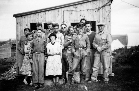 Steinunn Björg Gunnarsdóttir sendi eftirfarandi upplýsingar: „Pabbi og mamma telja að myndin sé tekin í Vatnsfirði í Vestur-Barðastrandarsýslu. Konurnar eru Laufey Böðvarsdóttir móðursystir mín frá Tungumúla (lengst til vinstri) og Björg Bjarnadóttir frá Rauðsdal, fyrir aftan hana stendur Hafliði Árnason frá Flatey. Annar frá [hægri] í fremstu röð (með hendur í vösum) er Samúel Bjarnason frá Rauðsdal. Fyrir aftan Samúel er Sigurjón Árnason frá Flatey (dökk peysa og hvít skyrta). Maðurinn í röndóttu peysunni er Einar Sigurbrandsson frá Grænhól. Væri gaman að sjá ef það eru til fleiri myndir frá þessum vinnuflokki.“ - / m-stae1-17355 frá Minjasafninu á Akureyri