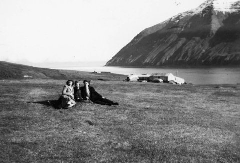 Myndin er tekin á hesthúsavellinum á Ytri-Á á Kleifum í Ólafsfirði. Í baksýn eru fjárhúsin á Ytri-Á og Múlinn. Fjárhúsin hafa breyst töluvert, helmingurinn af þeim hefur verið rifinn og hlutinn þar sem lægra þakið á myndinni er var hækkaður og settur hærri stafn og brattara þak.
Konurnar tvær eru sagðar dætur Finns Björnssonar og Mundínu Freydísar Þorláksdóttur sem eignuðust 20 börn saman og bjuggu á neðri hæðinni á Ytri-Á. Lesandi taldi að konurnar gætu verið Stefanía Gunnlaug og Birna en Laufey systir þeirra var einnig nefnd. Ekki er enn vitað hvaða barn er á milli þeirra. - / m-stae1-17478 frá Minjasafninu á Akureyri