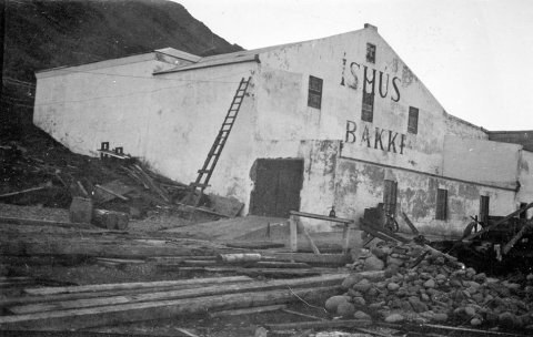 Þetta er söltunarstöðin Bakki á Siglufirði. Pétur J. Thorsteinsson á Bíldudal byggði hús með sama nafni steinsnar frá, 1917 að því talið er, og sumar heimildir herma að Pétur hafi einnig byggt söltunarstöðina á árunum 1916-1919 en á vef Síldarminjasafns Íslands á Siglufirði segir í grein eftir Benedikt Sigurðsson: „Eitt af fyrirtækjum Óskars Halldórssonar, Hrogn og lýsi h.f., byggði íshúsið á söltunarlóð sinni í Bakka 1925.“  - / m-stae1-17595 frá Minjasafninu á Akureyri