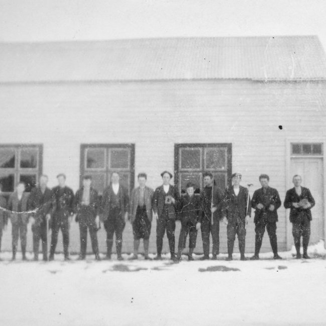 Munkaþverá í Eyjafirði. Mennirnir standa fyrir framan Ungmennafélagshúsið, samkomuhús sem Ungmennafélagið Ársól lét reisa um 1924 en var rifið einhvern tíma milli 1980 og 1990. Minjasafnið á Akureyri / Album 54-52