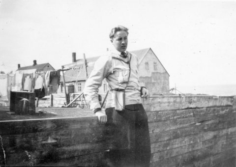 Þetta er Jóhann Kristinn Daníelsson; Jói Dan, kennari, söngvari og lífskúnstner, fæddur 18.11. 1927, dáinn 23.11. 2015. Hann gæti verið um tvítugt á myndinni að því talið er. Jóhann bjó og starfaði lengst af á Akureyri og á Dalvík. Myndin er tekin á Blönduósi, húsið að baki Jóhanns er Pétursborg en fjær hús Snorra Arnfinnssonar hótelstjóra - Minjasafnið á Akureyri / Album 56-48