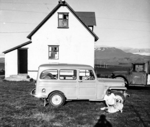 Myndin er tekin á bænum Leirubakka í Landsveit. Húsið á myndinni er „gamli bærinn sem búið er að rífa núna, ábúendur á þessum tíma voru Magnús Sigurðsson og Jóhanna Jónsdóttir,“ skrifaði Gunnar Sigurjónsson í skeyti til Akureyri.net. Magnús og Jóhanna voru afi hans og amma.

Stúlkan á myndinni er Jóhanna Sigurjónsdóttir, systir Gunnars. Honum sýndist það og Jóhanna staðfesti að svo sé. Hundurinn á myndinni hét Kópur, segir Jóhanna og bætir við að myndin sé tekin á tímabilinu 1963 til 1965.

Jóhanna segist hafa verið mörg sumur í sveit hjá afa sínum og ömmu á Leirubakka. Móðurbræður hennar áttu hins vegar bílana á myndinni; nær er Willys Overland árgerð 1951, segir Jóhanna, sem notaður var til að fara í réttir í Réttarnesi. „Bekkir voru sitt hvoru megin aftur í og þar var spjallað, sungið og teigaðar guðaveigar, þar smakkaði ég ginger ale í fyrsta sinn – var notað sem bland.“

Hinn bíllinn er Vibon, sennilega árgerð 1948 að sögn Jóhanna. Sá var notaður þegar fairð var í veiðiferðir í Veitivötn á Landmannaafrétti, að sögn hennar.