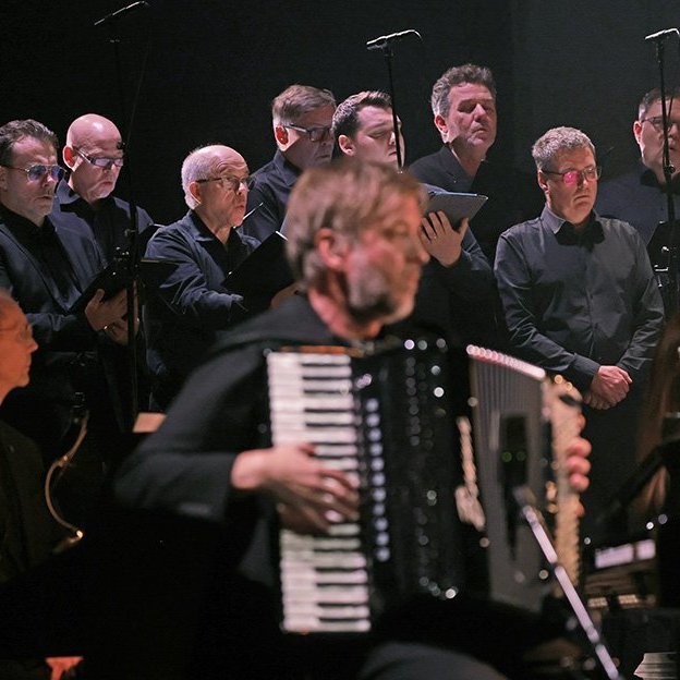 Tónleikarnir „Ljós og myrkur“: Söngsveit SinfoniaNord á sviðinu og Atli Örvarsson leikur á harmoniku – Tónlist Atla flutt í Hofi á skírdag 2026. Mynd: Skapti Hallgrímsson